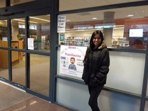 Ishika standing next to her campaign poster.